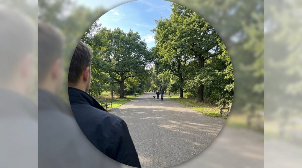 Simulation d'une vision en tunnel montrant une allée de parc nette au centre et un flou prononcé sur les côtés.